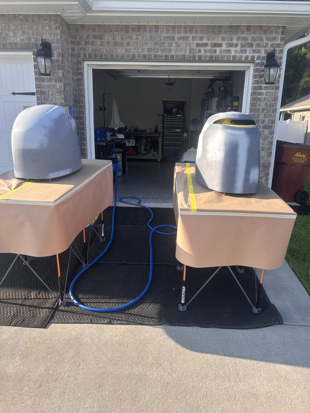 Two boat motor covers set up for paint in a home driveway