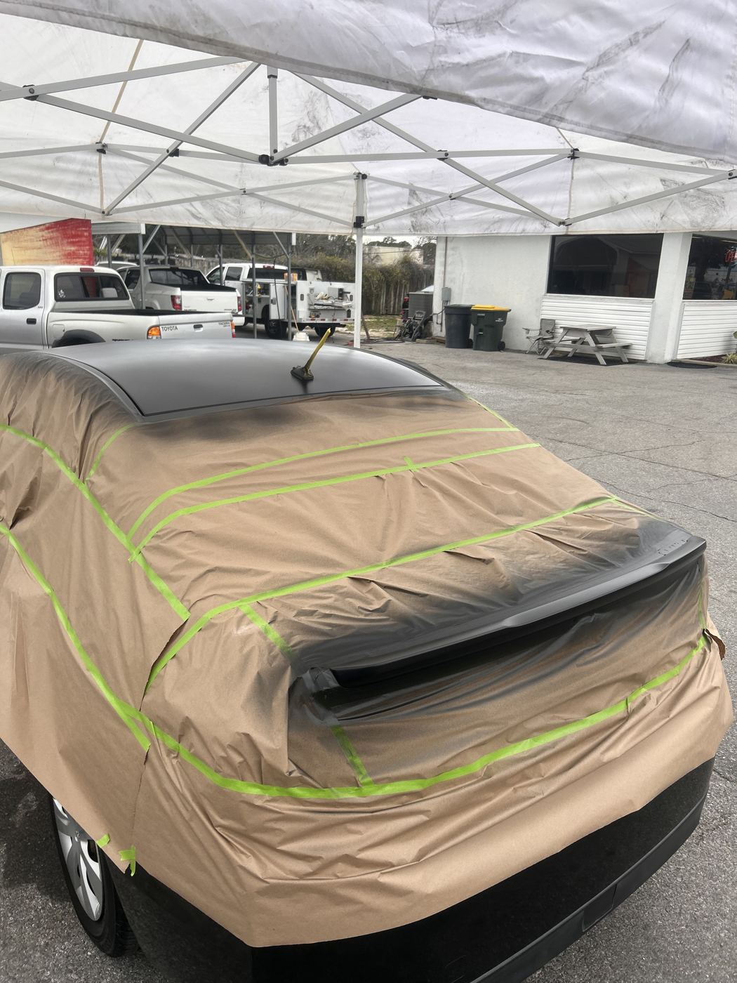Car masked under a pop-up canopy for painting